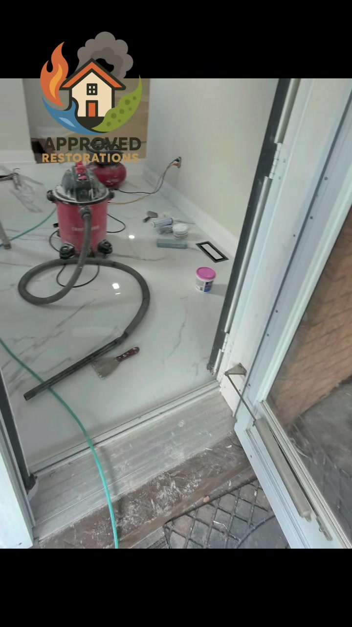 After a major flood wiped out three floors of this Vaughan home, our crew is pushing through the final stages of the rebuild, firing up the shop vac and air compressor by the open entryway to clear out construction dust, patch the baseboards, and prep the newly laid tile for the homeowner.